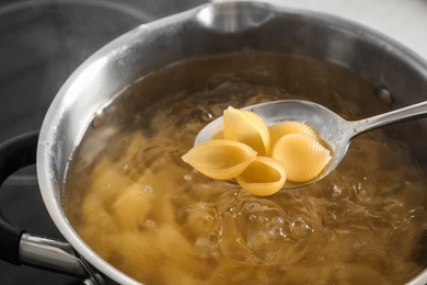 Photo of Cooking pasta in pot on stove, closeup view