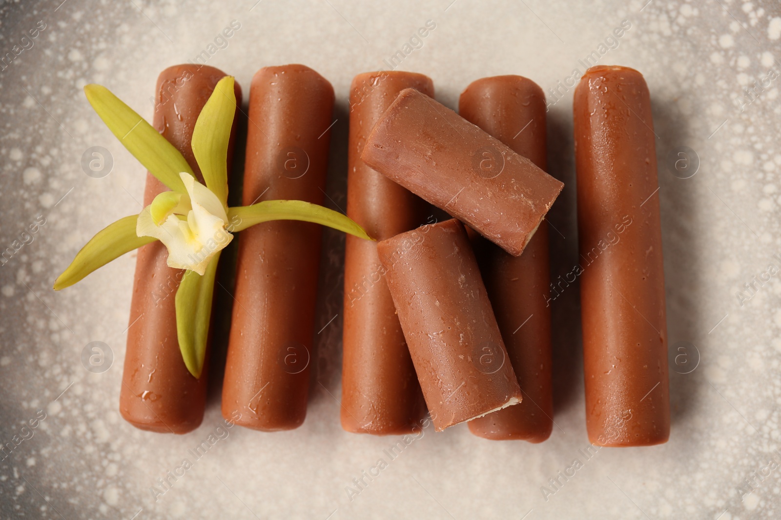 Photo of Glazed curd cheese bars and vanilla flower on plate, top view