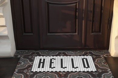 Stylish door mat with word HELLO near entrance