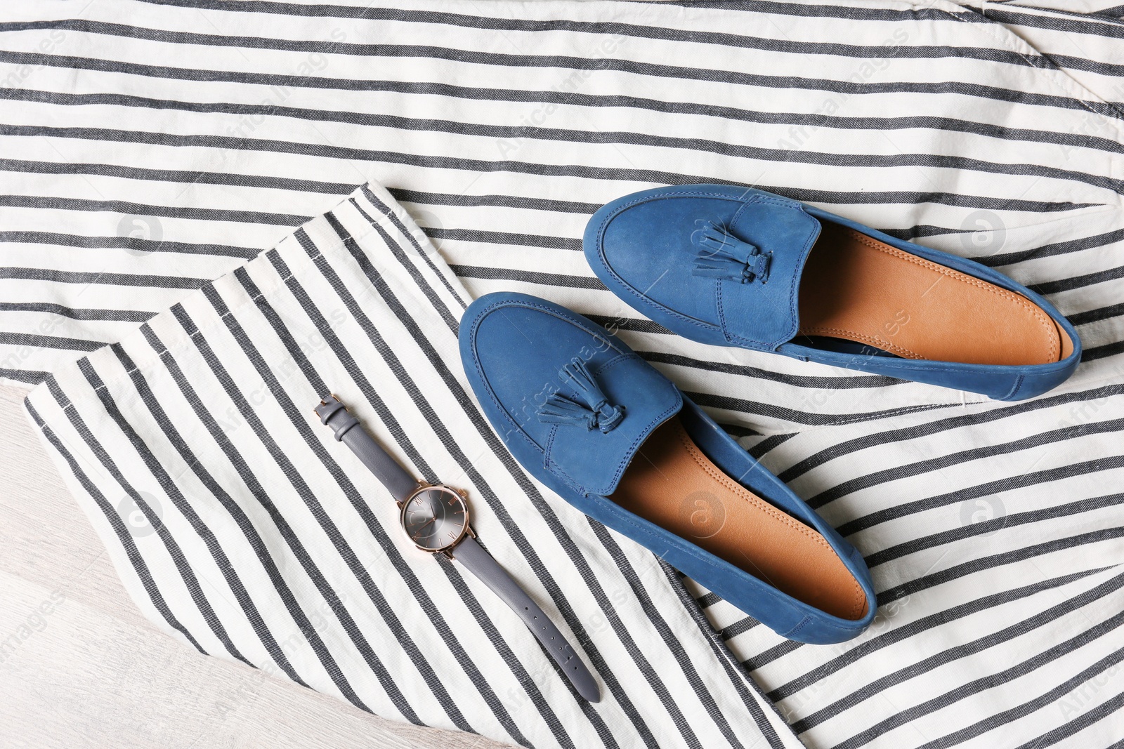 Photo of Pair of female shoes and wristwatch on clothes, top view