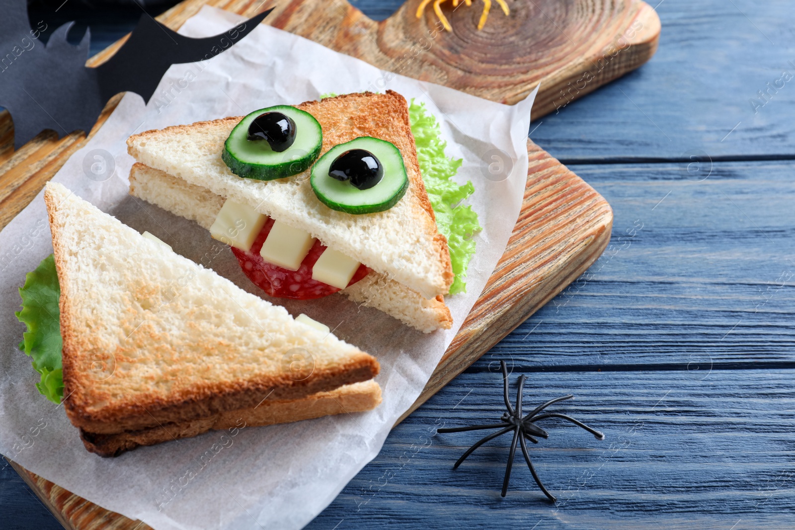 Photo of Cute monster sandwich served on blue wooden table, closeup. Halloween party food