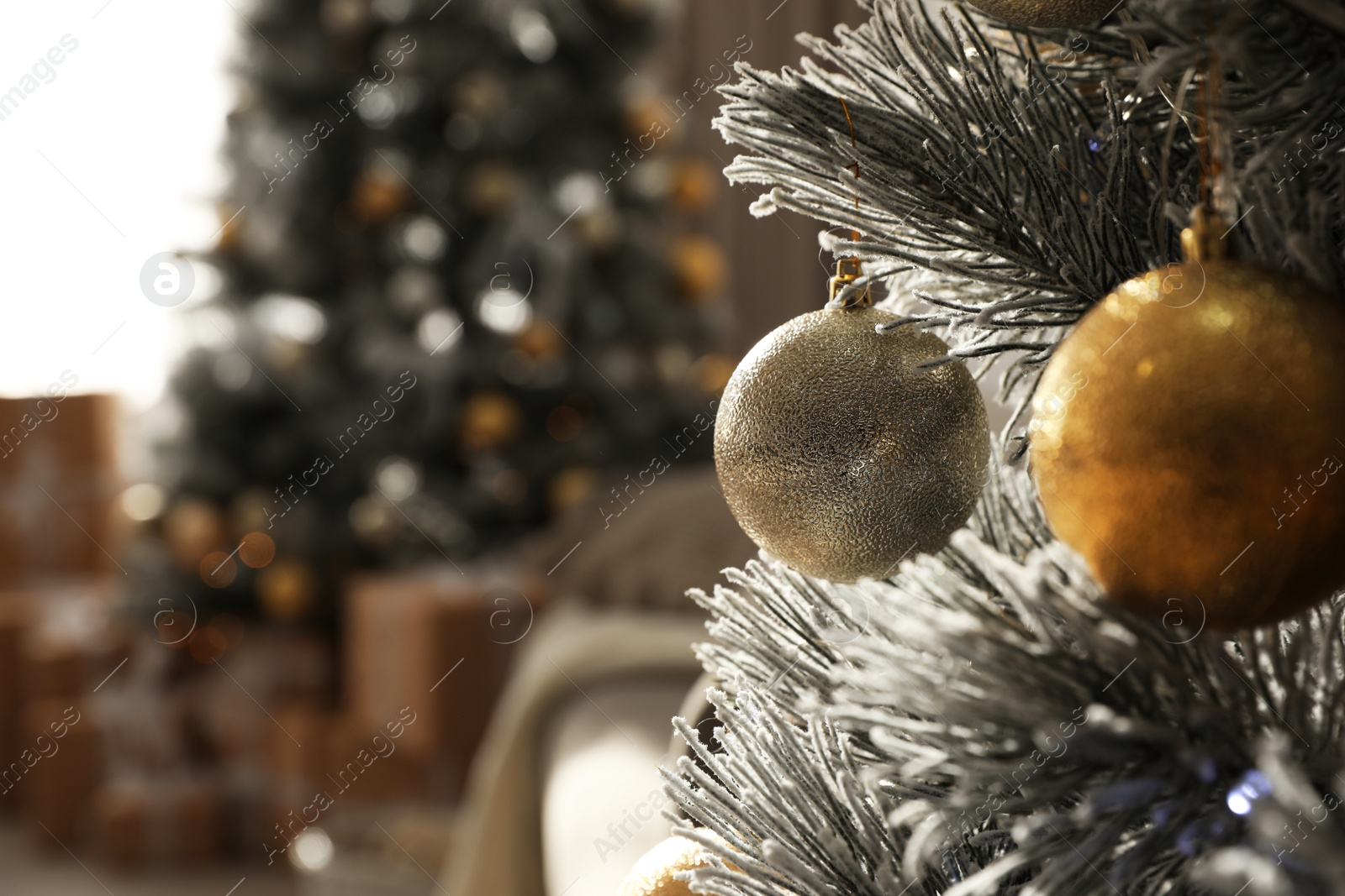 Photo of Christmas ball hanging on tree in stylish room interior