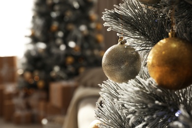 Christmas ball hanging on tree in stylish room interior