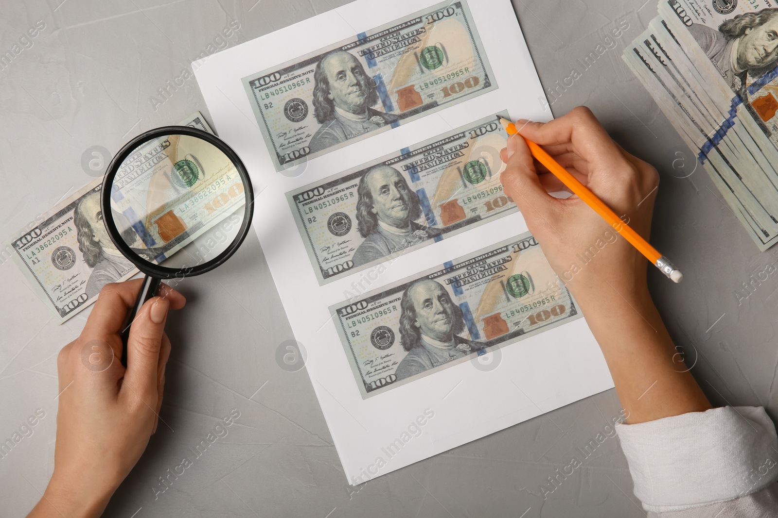 Photo of Counterfeiter drawing dollar banknotes with pencil at grey table, top view. Fake money concept