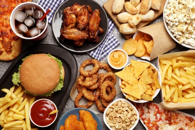 Photo of French fries, burger and other fast food on gray table, flat lay