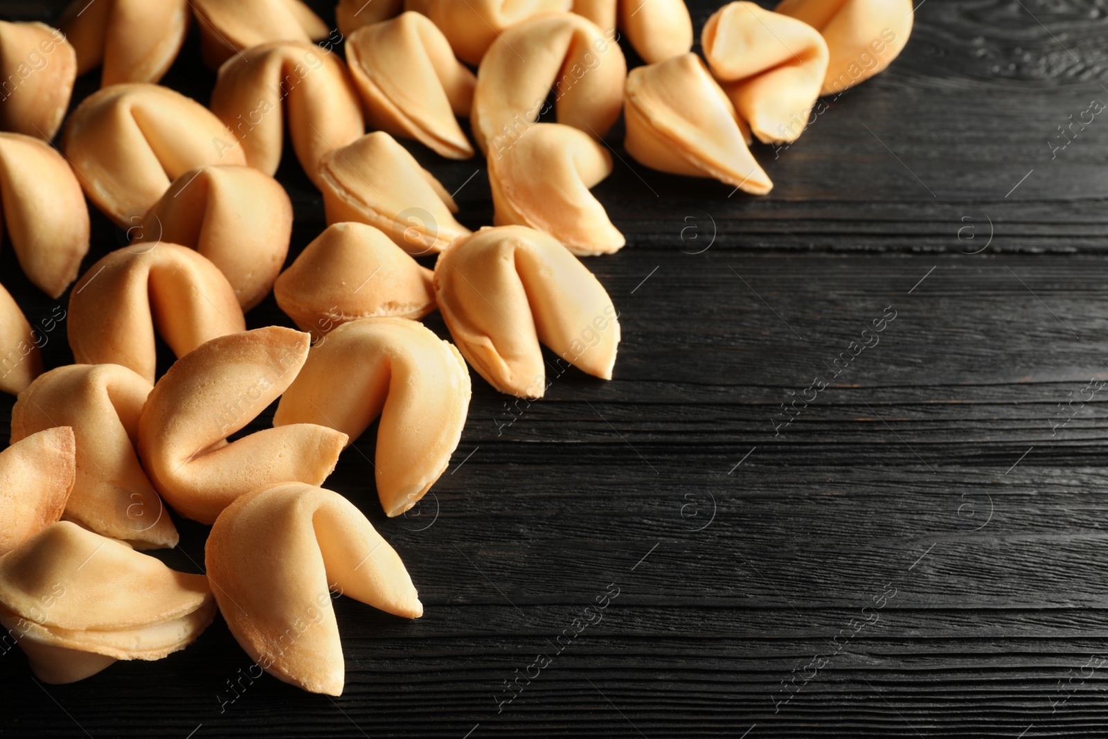 Photo of Tasty fortune cookies with predictions on black wooden table, space for text