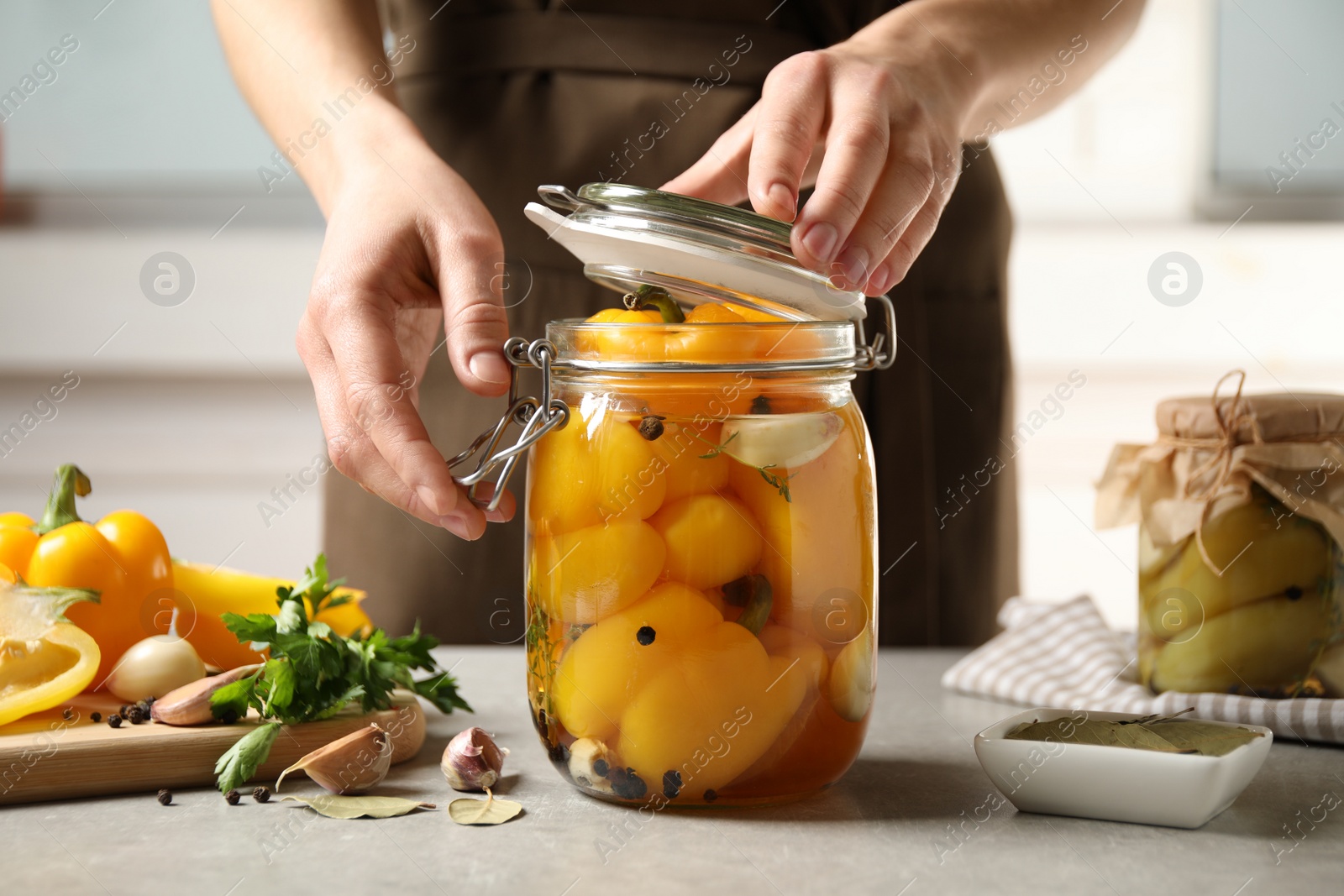 Photo of Woman with jar of pickled peppers at table, closeup