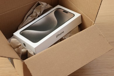 Leiden, Netherlands - October 6, 2023: New iPhone 15 Pro Max and crumpled paper in cardboard box on table, closeup. Amazon delivery