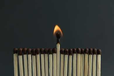 Burning match among unlit ones on black background, closeup