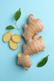 Photo of Fresh ginger with green leaves on pale light blue background, flat lay