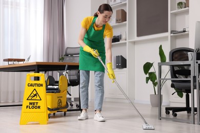 Photo of Cleaning service. Woman washing floor with mop in office