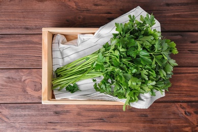 Crate with fresh green parsley on wooden background, top view