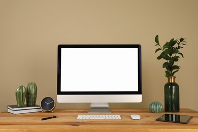 Modern computer and decor on wooden table near beige wall