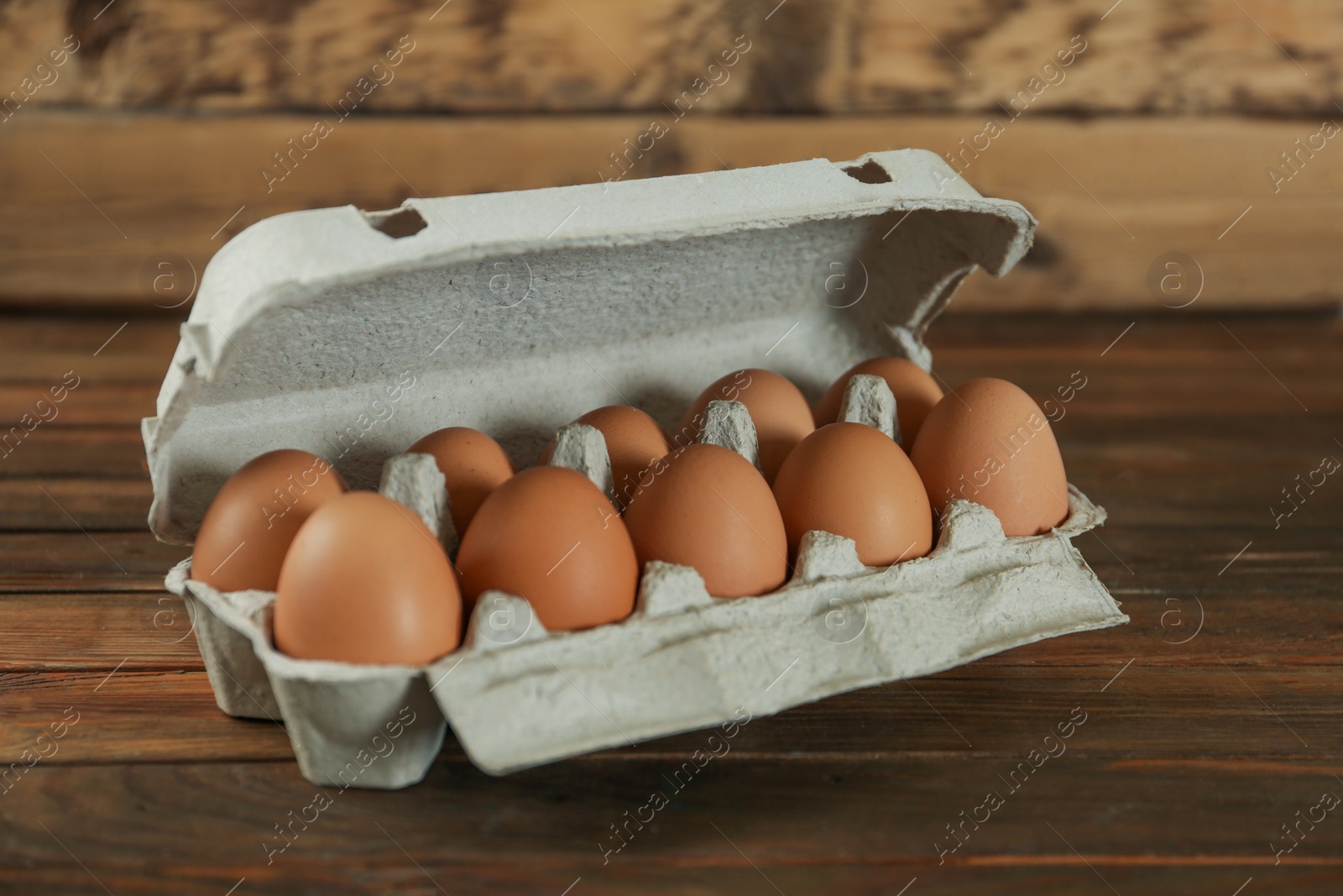 Photo of Raw chicken eggs in carton on wooden table