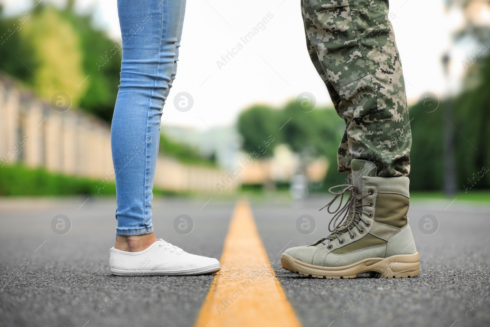 Photo of Man in military uniform and young woman separated by yellow line on road, closeup