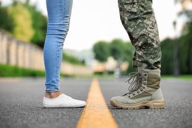 Photo of Man in military uniform and young woman separated by yellow line on road, closeup