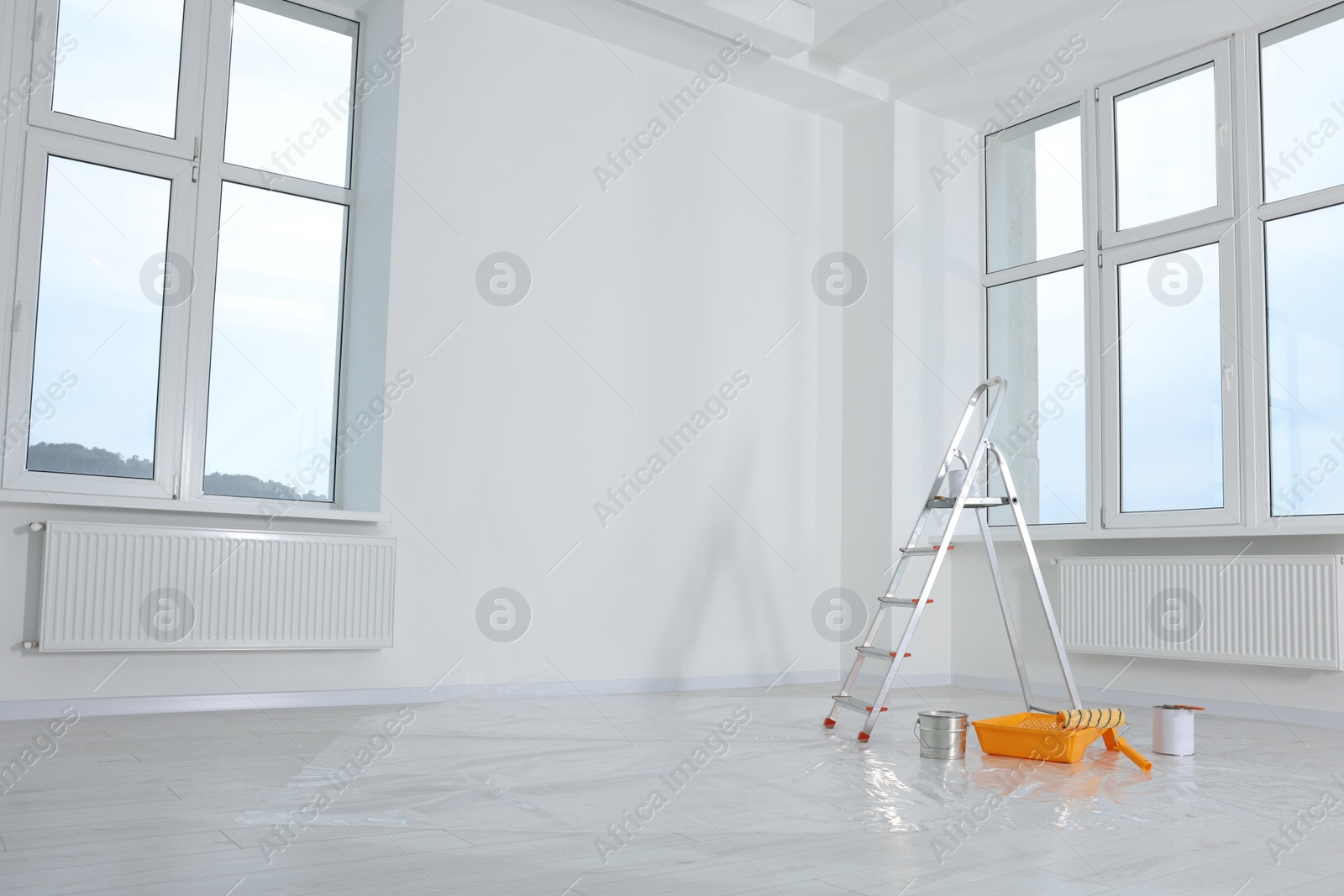 Photo of Stepladder and painting tools near window in empty room, space for text