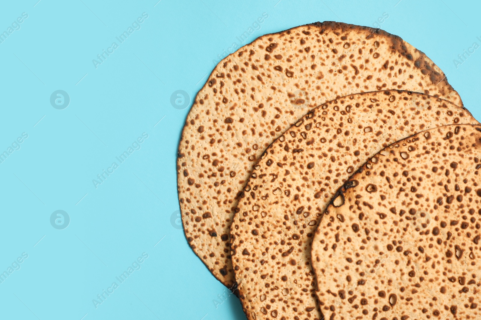 Photo of Tasty matzos on light blue background, flat lay with space for text. Passover (Pesach) celebration