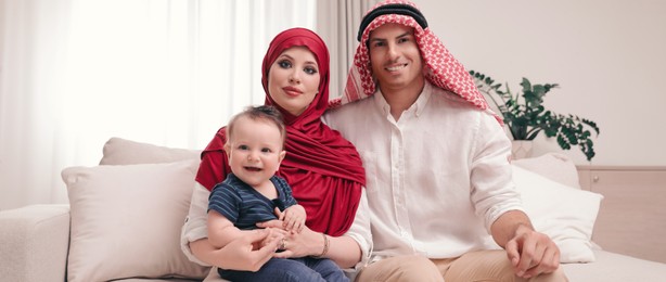 Image of Happy Muslim family with little son in living room. Banner design 