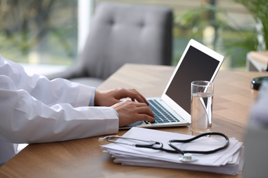 Photo of Professional doctor working on laptop in office, closeup