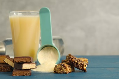 Photo of Different energy bars, protein cocktail and powder on blue wooden table