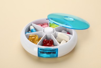 Plastic box with different pills on beige background
