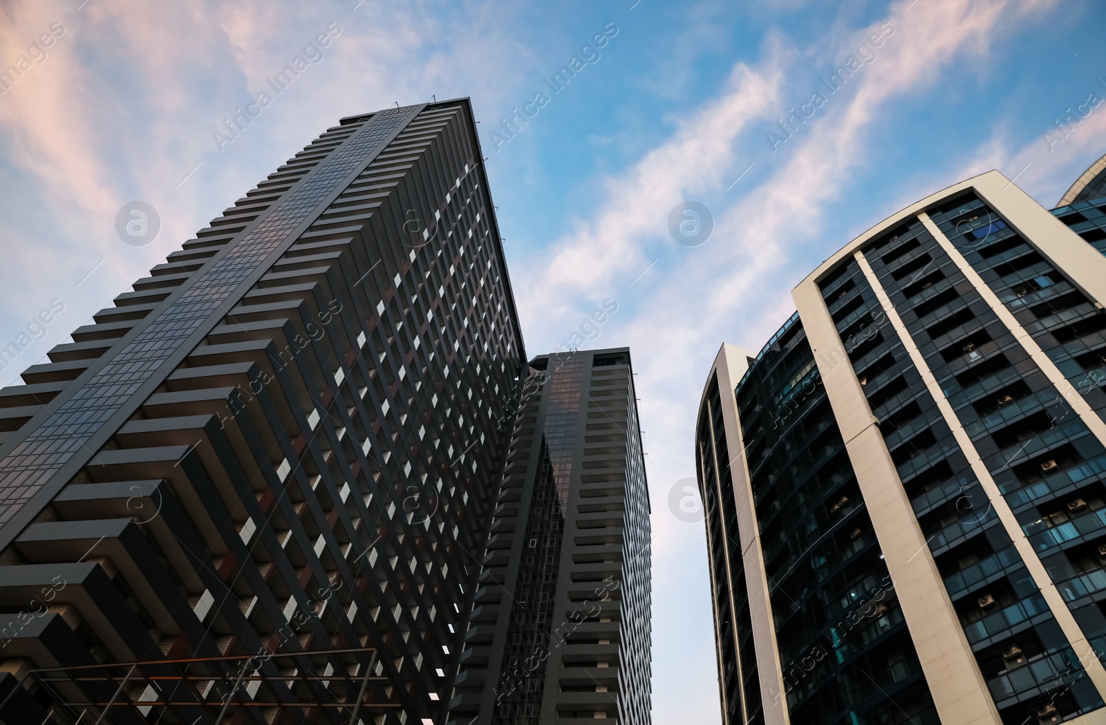 Photo of Beautiful skyscrapers on city street in evening, low angle view