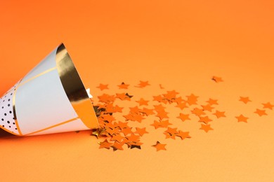 Party hat and confetti on orange background