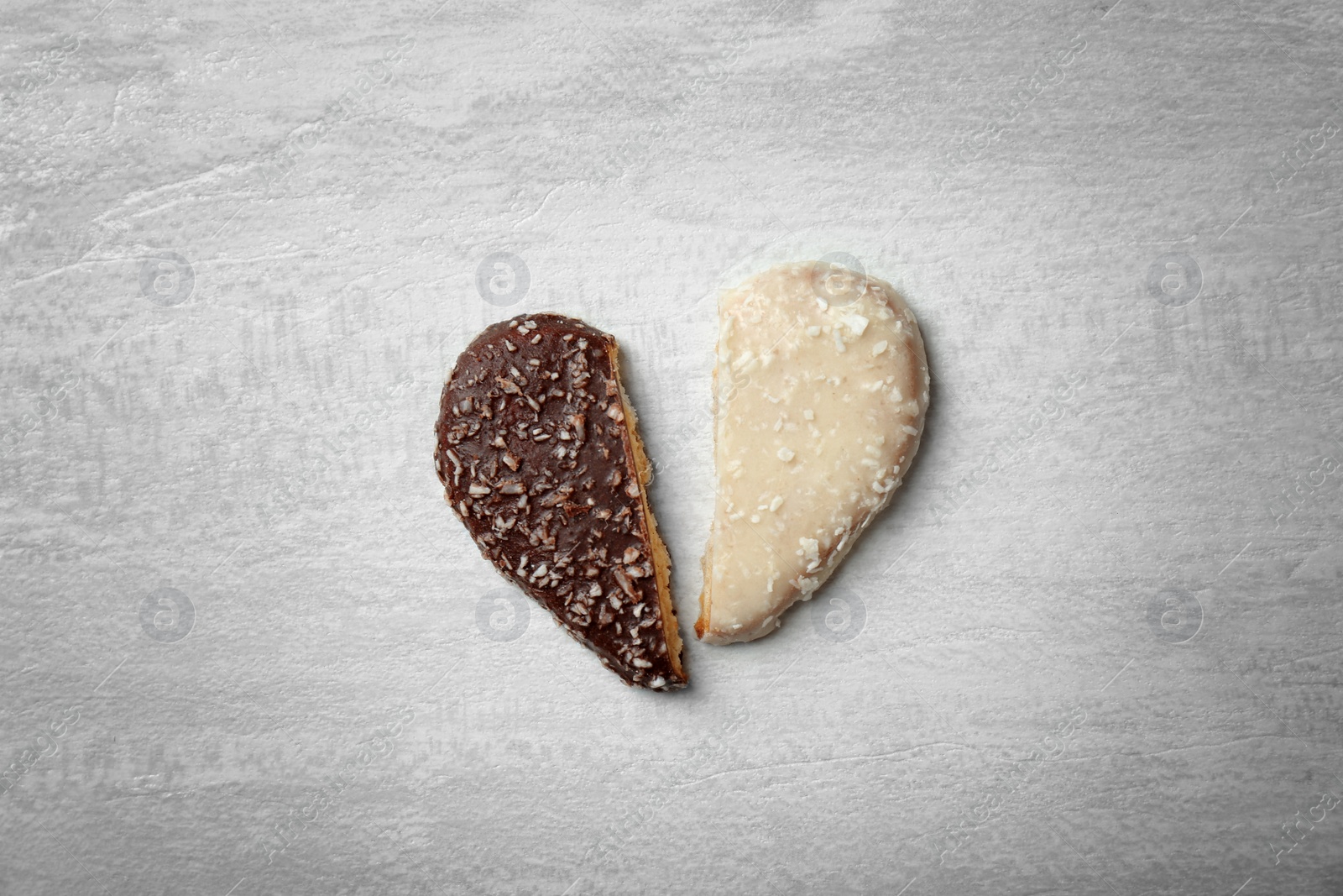 Photo of Halves of heart shaped cookies on gray background, top view. Relationship problems