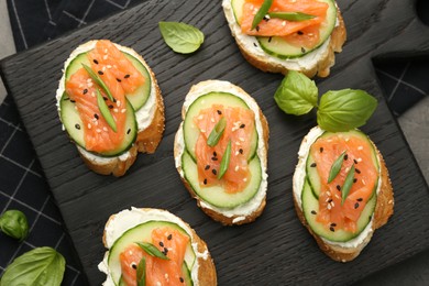 Photo of Tasty canapes with salmon, cucumber and cream cheese on grey table, top view