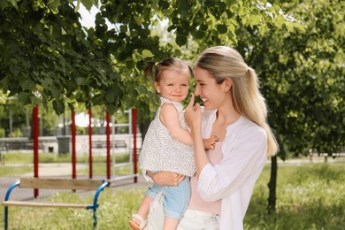 Happy mother with her daughter spending time together in park. Space for text