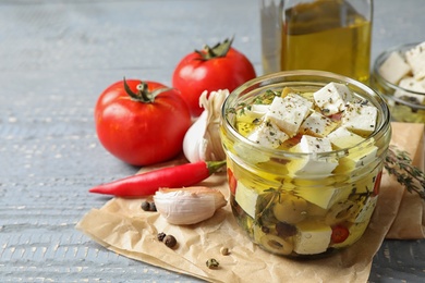 Photo of Composition with pickled feta cheese in jar on grey wooden table, space for text