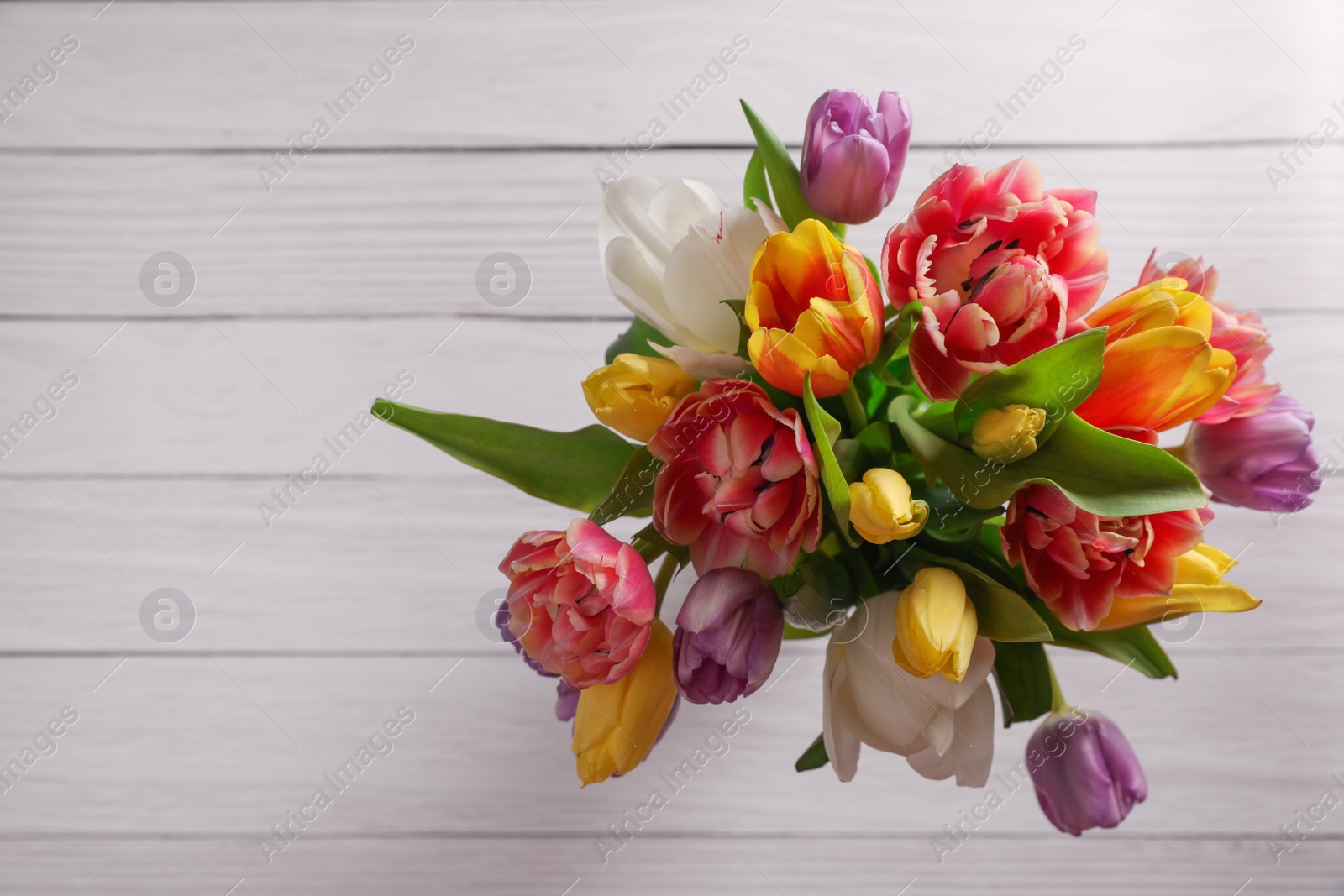 Photo of Bouquet of beautiful tulips on white wooden table, top view. Space for text