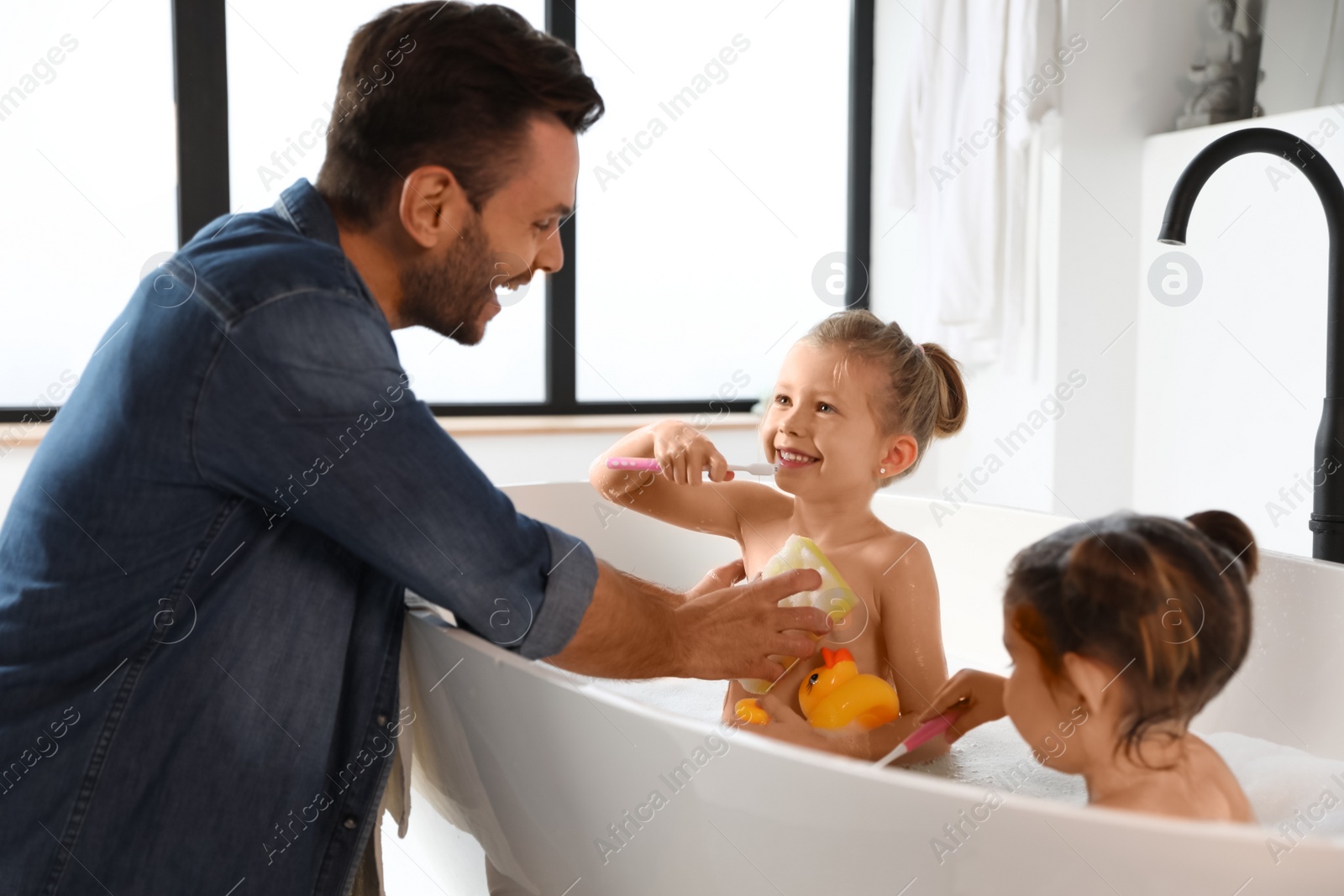 Photo of Young father with little daughters in bathroom