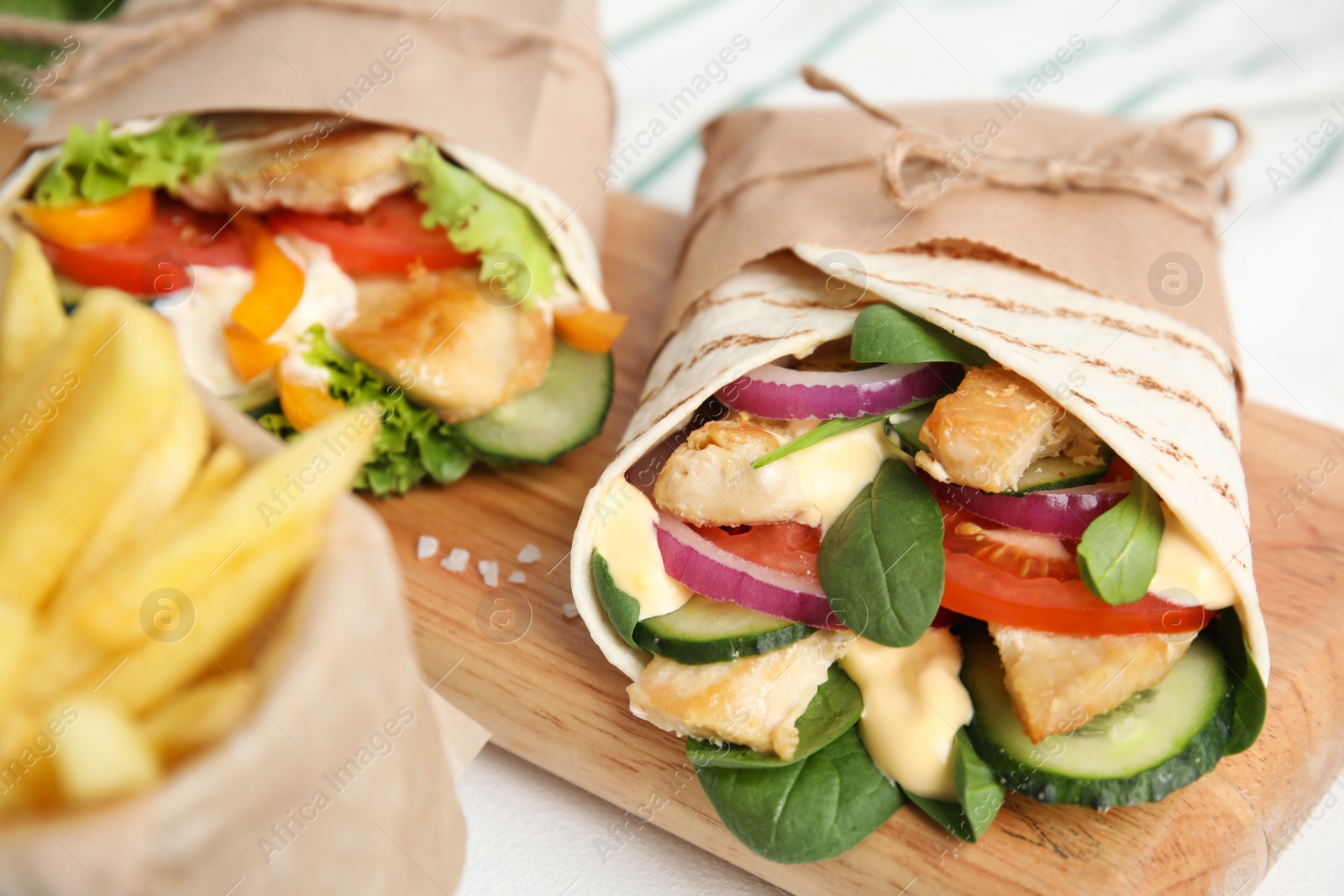 Photo of Delicious shawarmas with chicken and fresh vegetables on white table, closeup