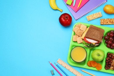 Photo of Flat lay composition with tray, tasty food and school stationery on light blue background. Space for text