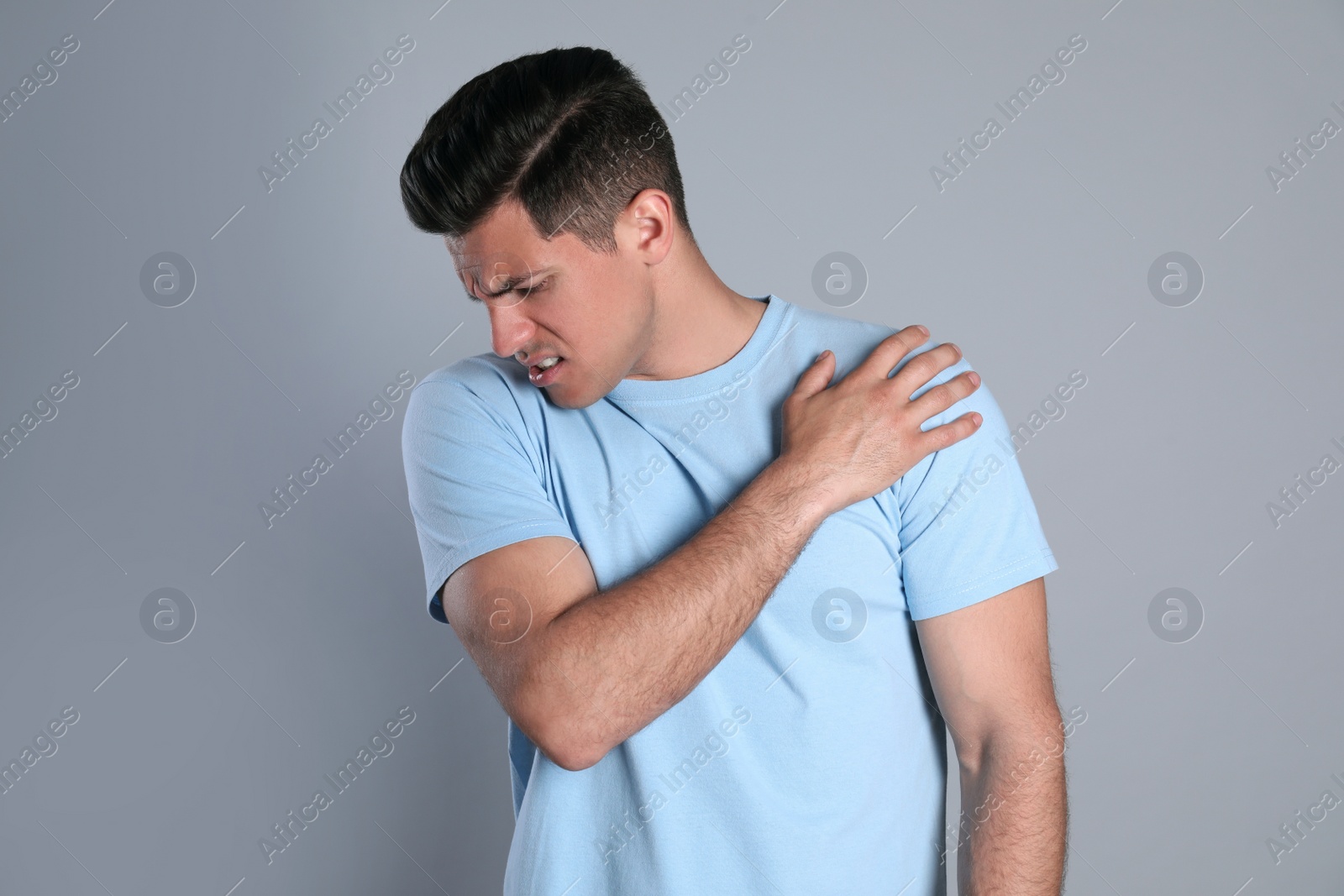 Photo of Man suffering from shoulder pain on grey background