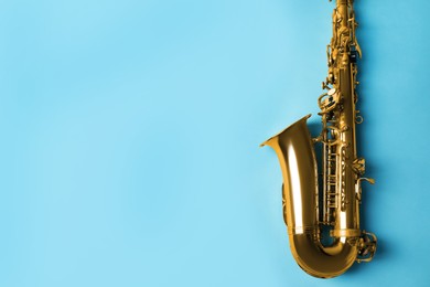 Photo of Beautiful saxophone on light blue background, top view. Space for text