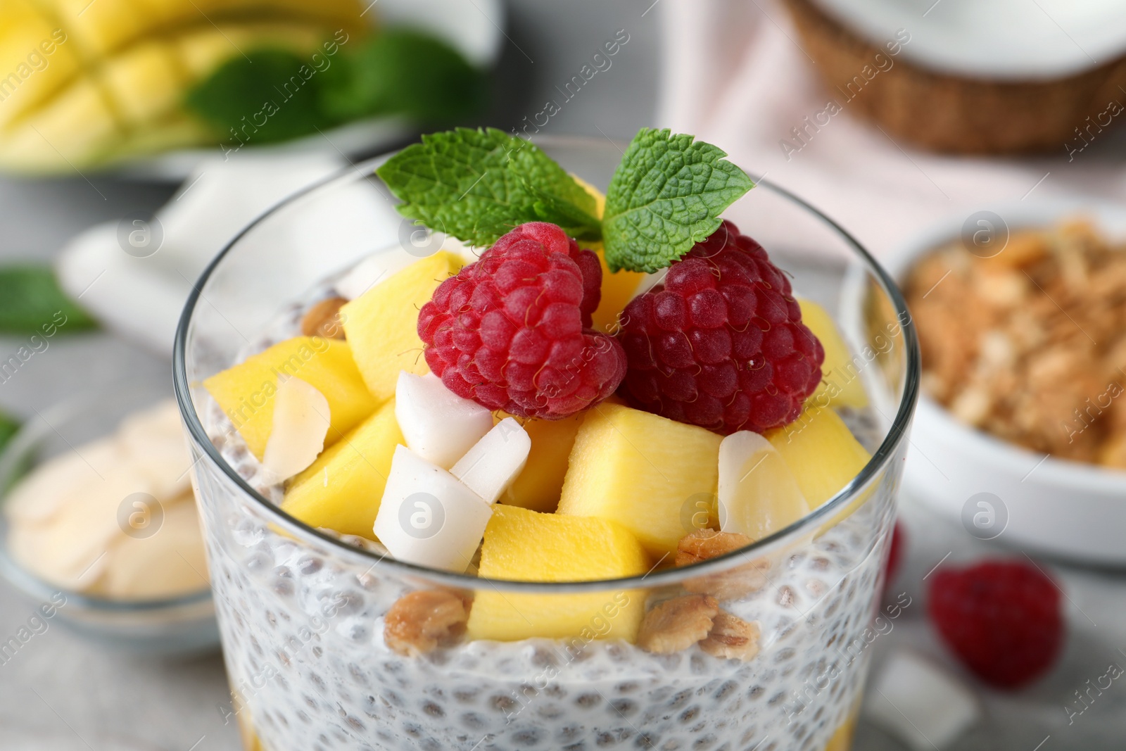 Photo of Delicious chia pudding with mango, raspberries and granola in glass, closeup