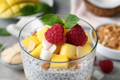 Photo of Delicious chia pudding with mango, raspberries and granola in glass, closeup