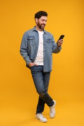 Photo of Smiling man with smartphone on orange background