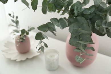 Photo of Beautiful eucalyptus branches on white table, closeup. Interior element
