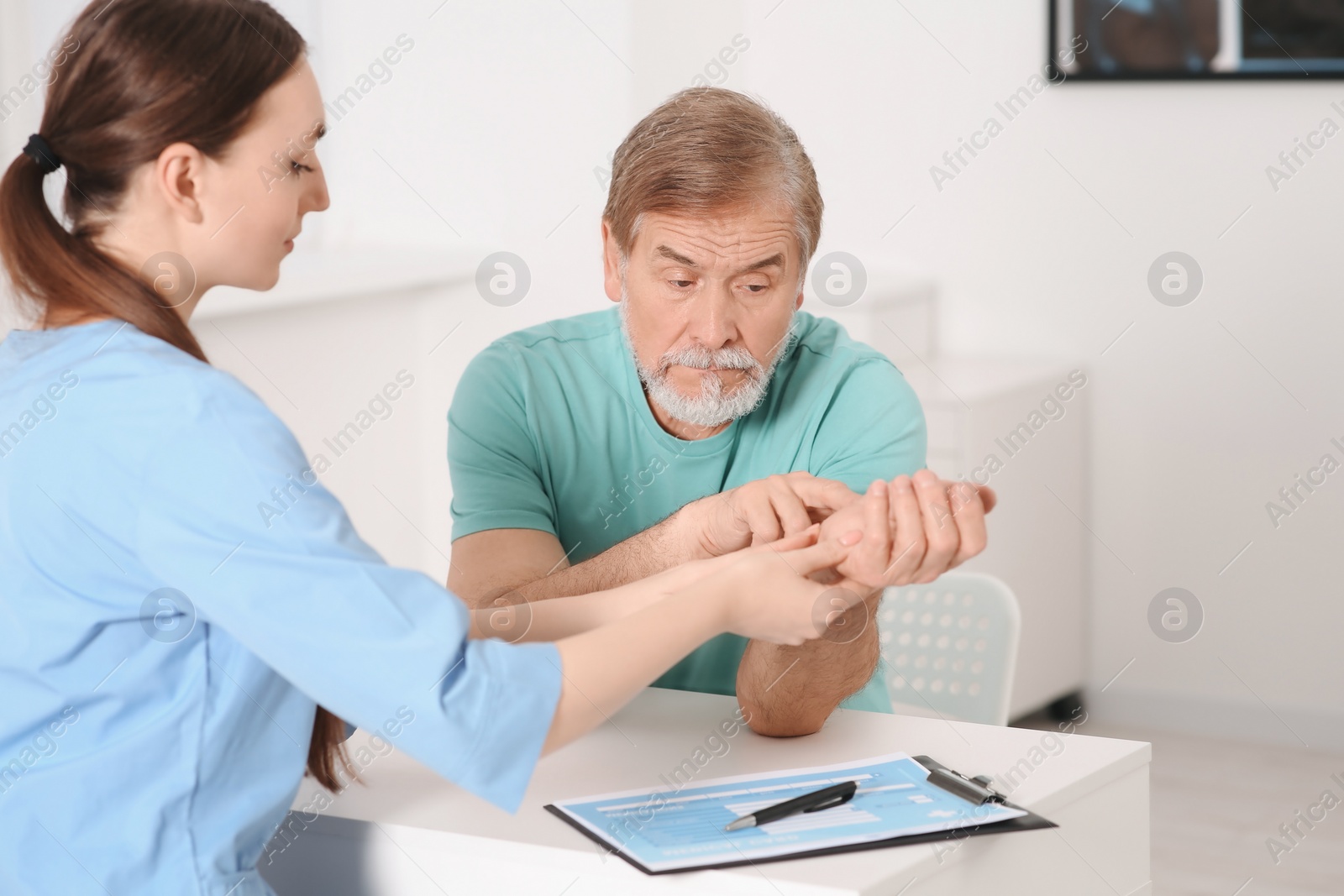 Photo of Orthopedist examining patient with injured hand in clinic