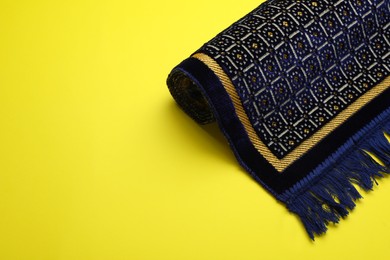 Muslim prayer rug on yellow background, space for text