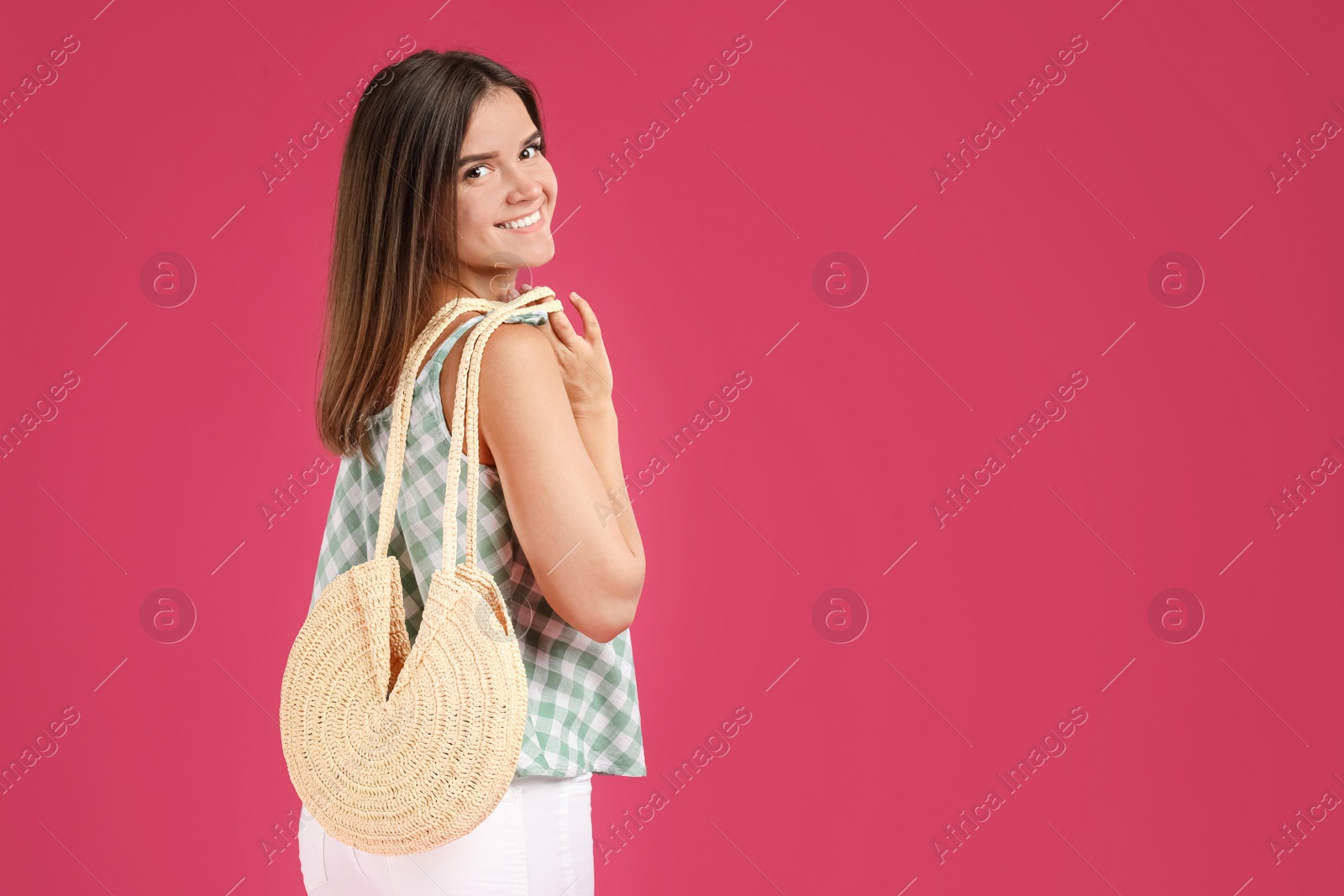 Photo of Young woman with stylish straw bag on pink background. Space for text