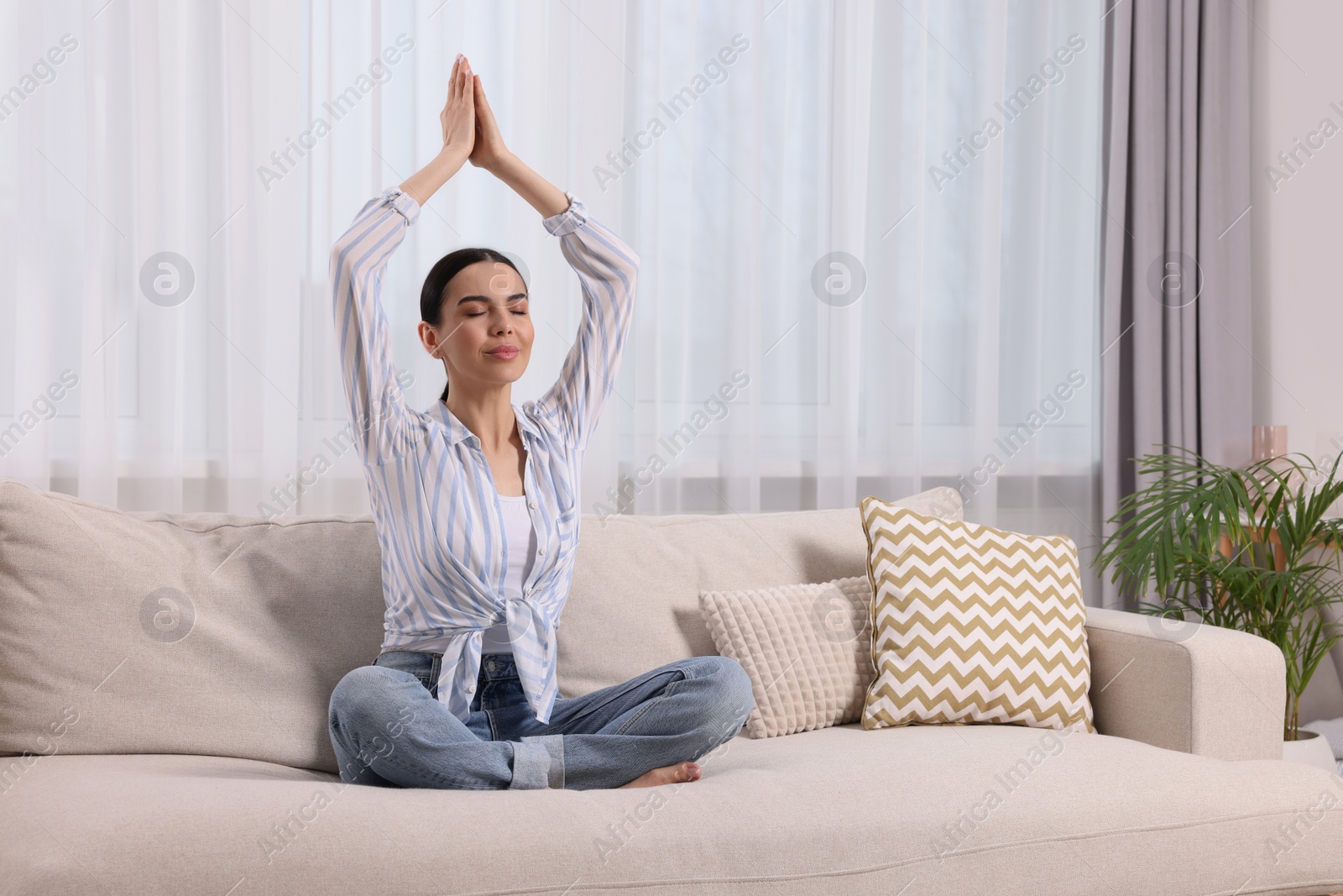 Photo of Woman meditating on sofa at home, space for text