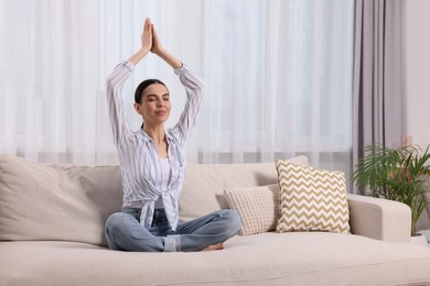 Photo of Woman meditating on sofa at home, space for text