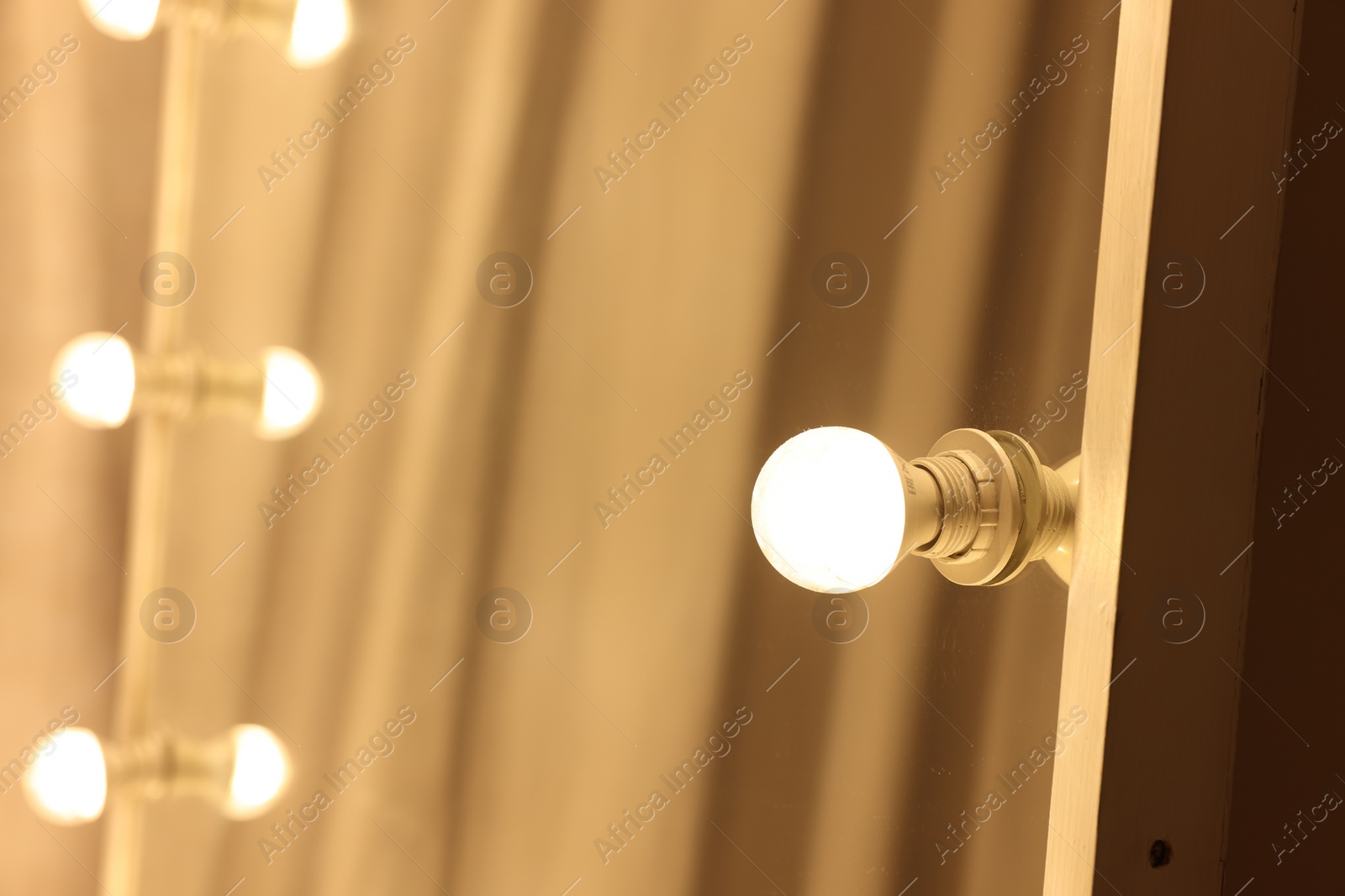 Photo of Modern mirror with light bulbs in makeup room, closeup