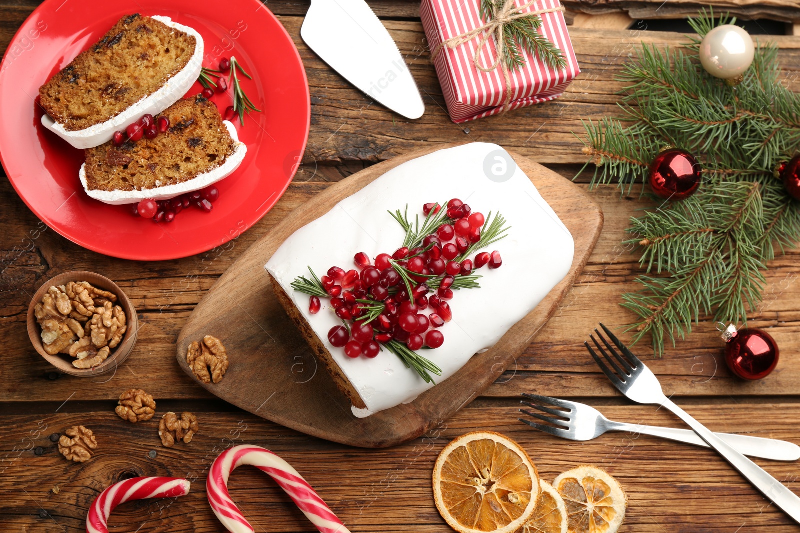 Photo of Flat lay composition with traditional classic Christmas cake with cranberries, pomegranate seeds and rosemary on wooden table