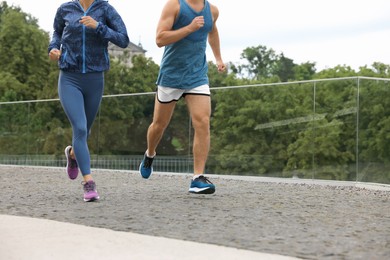 Photo of Healthy lifestyle. Sporty couple running outdoors, closeup. Space for text